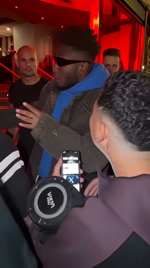 A man freestyling in a doorway in front of a crowd with a portable speaker